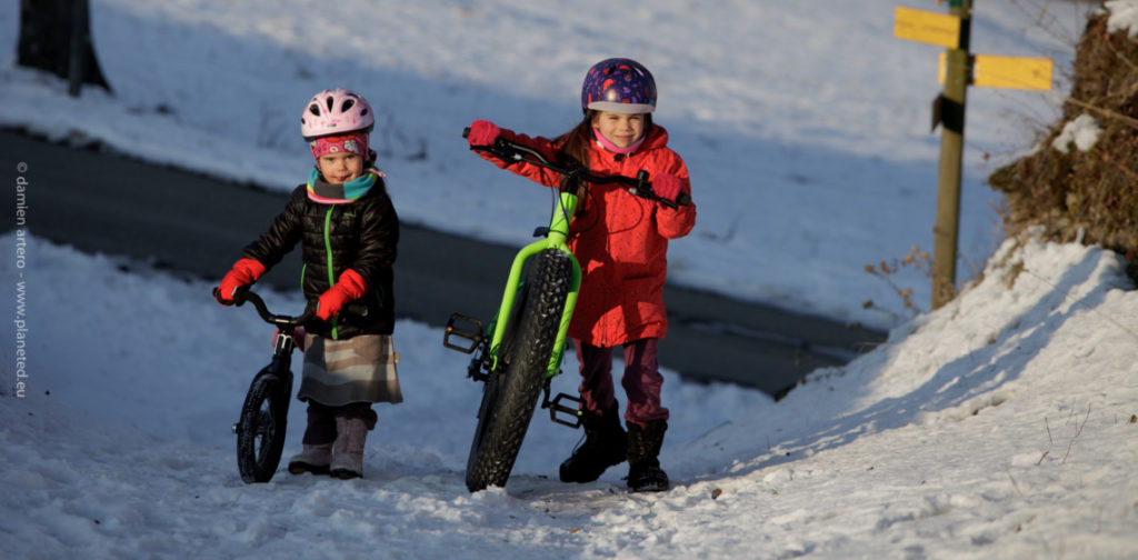 Deux enfants avec des vélos dans la neige