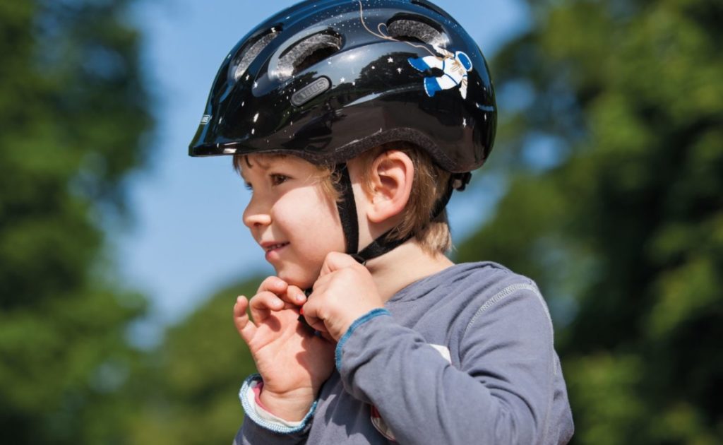 Enfant en train d'attacher son casque de vélo noir