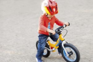 Enfant sur sa draisienne, protégé par un casque