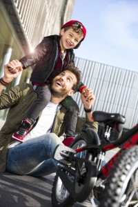 Père et son fils souriant devant un vélo enfant