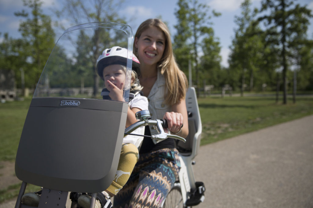 Jeune maman avec son enfant sur porte bébé avant vélo