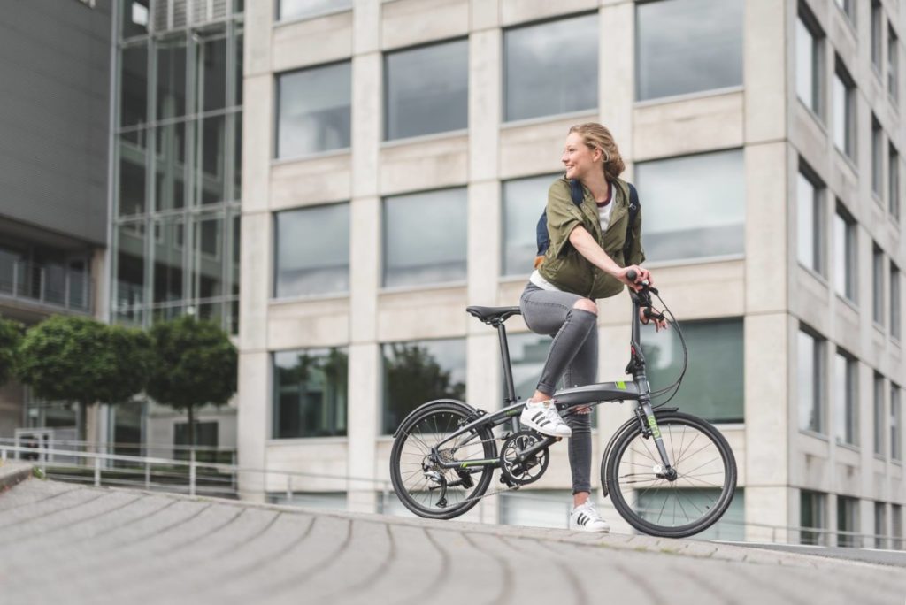 Jeune femme sur un vélo pliant à l'arrêt