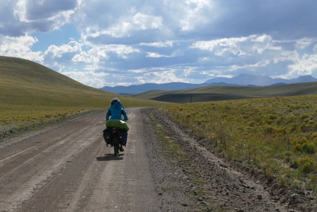 Femme cycliste en voyage à vélo s'éloignant sur la route