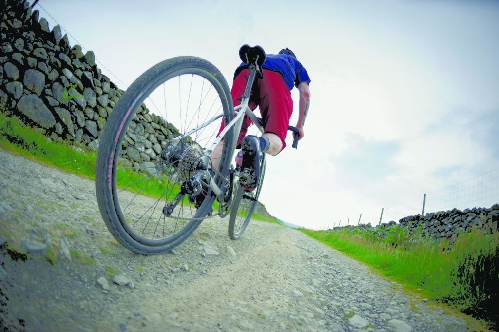 Cycliste roulant sur un vélo gravel sur une route non revêtue