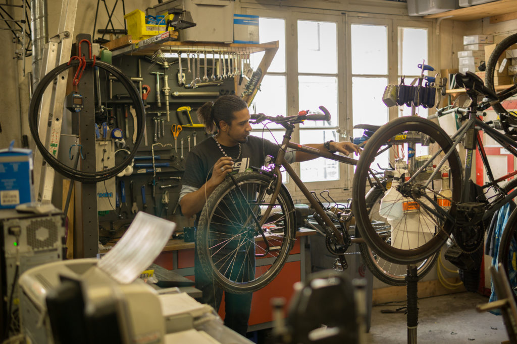 Mécanicien dans l'atelier de Cyclable Montpellier centre, travaillant sur un vélo trekking