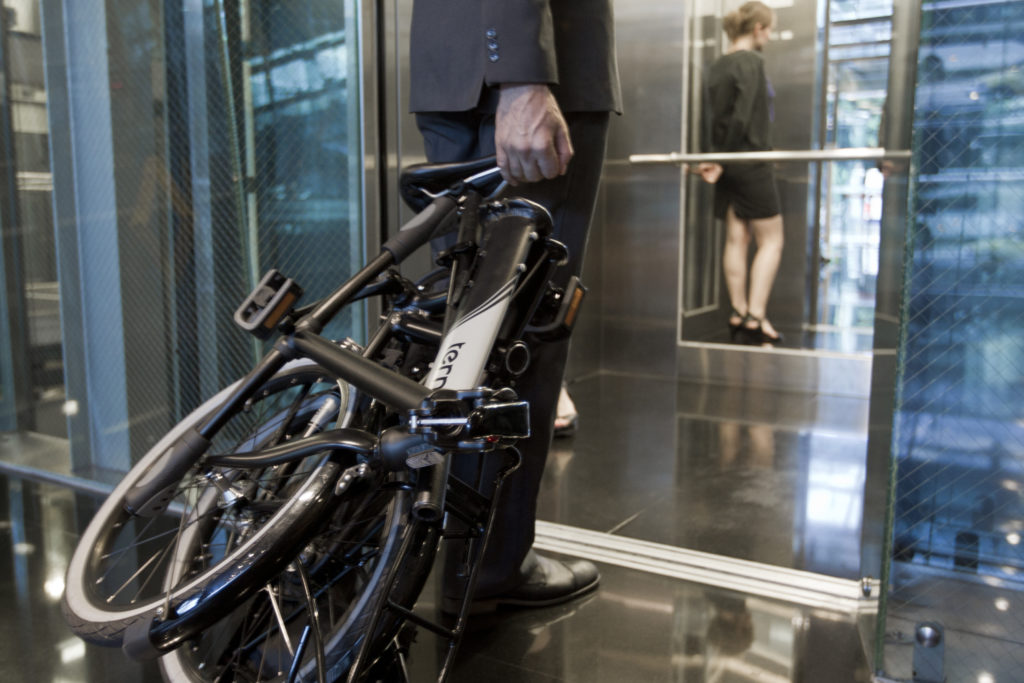 Homme qui rentre dans un ascenseur avec son vélo pliant