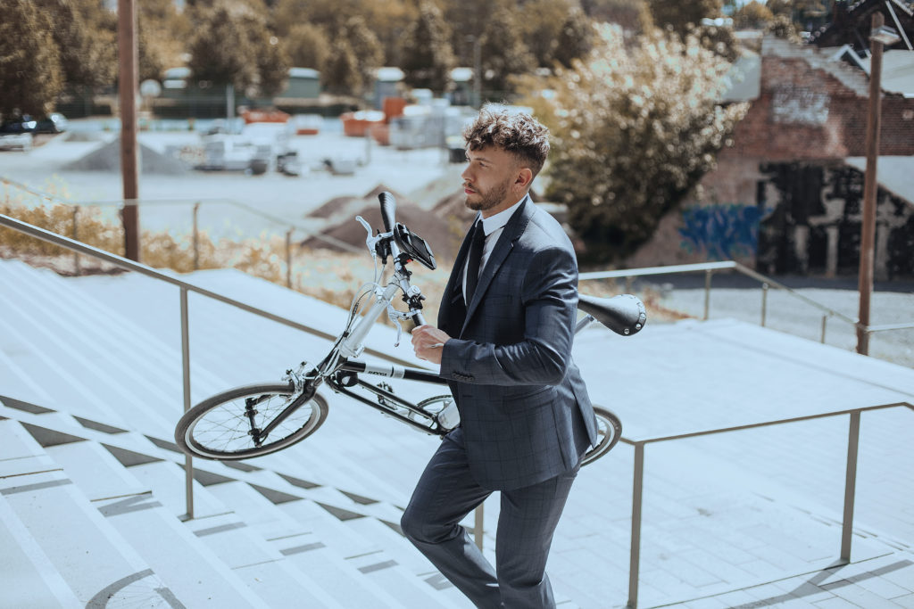 Homme montant les escaliers avec un vélo pliant déplié sous le bras