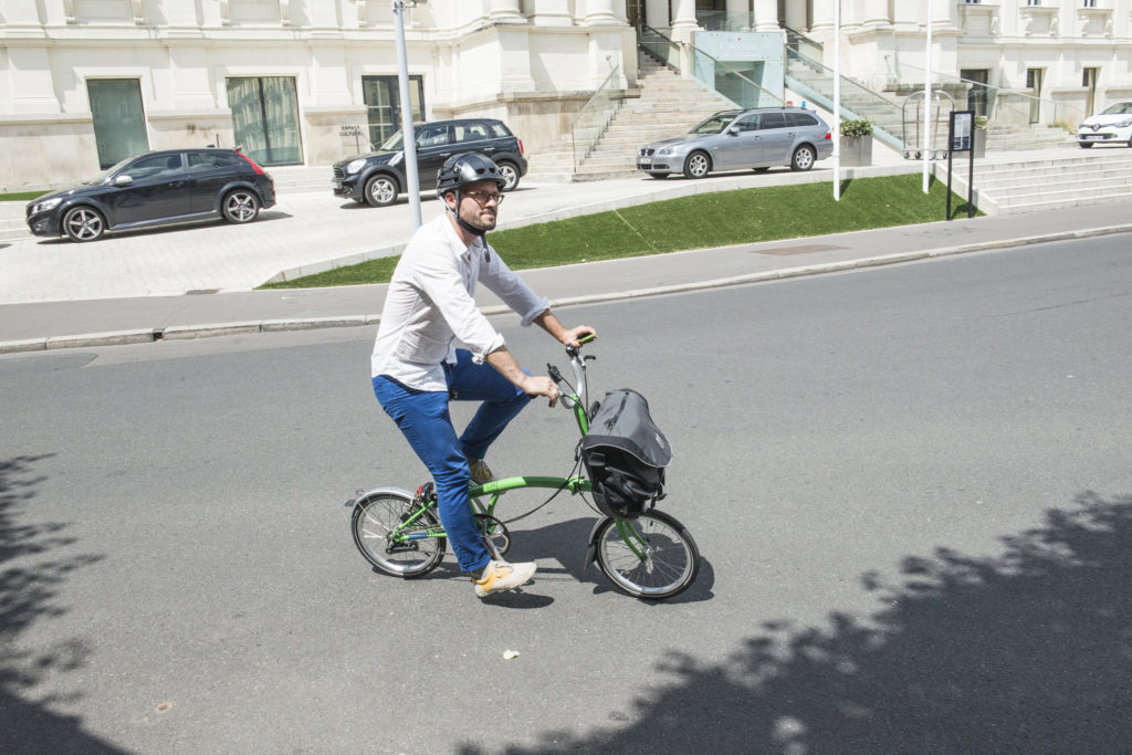 Cycliste sur un vélo pliant Brompton vert avec une sacoche avant