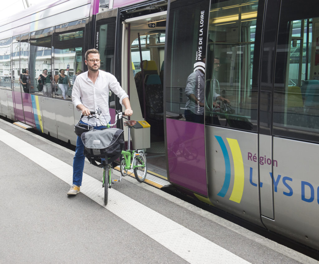 Cycliste qui sort d'un tram avec son vélo pliant déplié