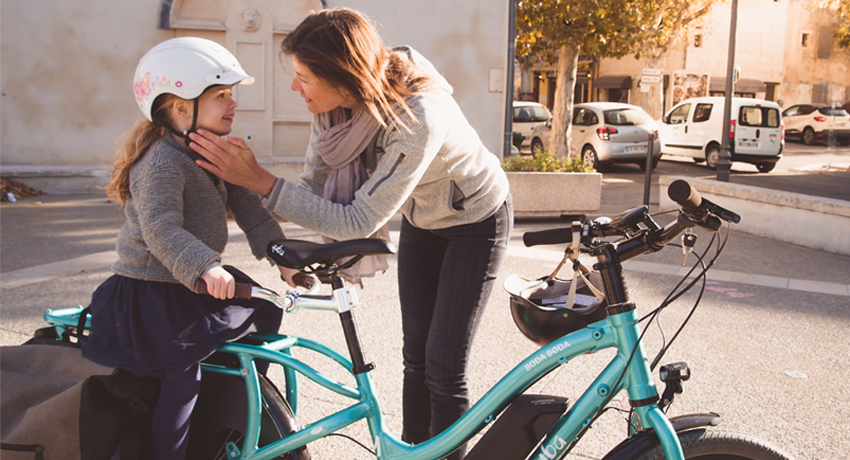 Mère attachant le casque de sa fille sur un vélo cargo Yuba Boda Boda