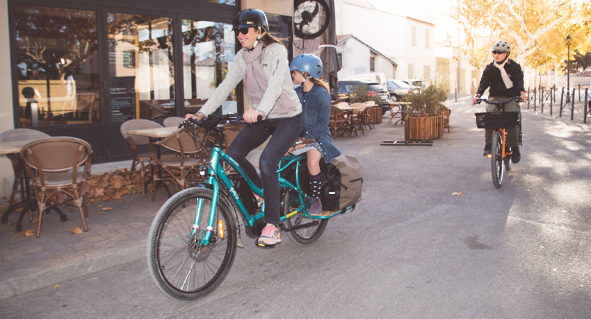 Parents transportant leurs enfants sur des vélos cargos Yuba
