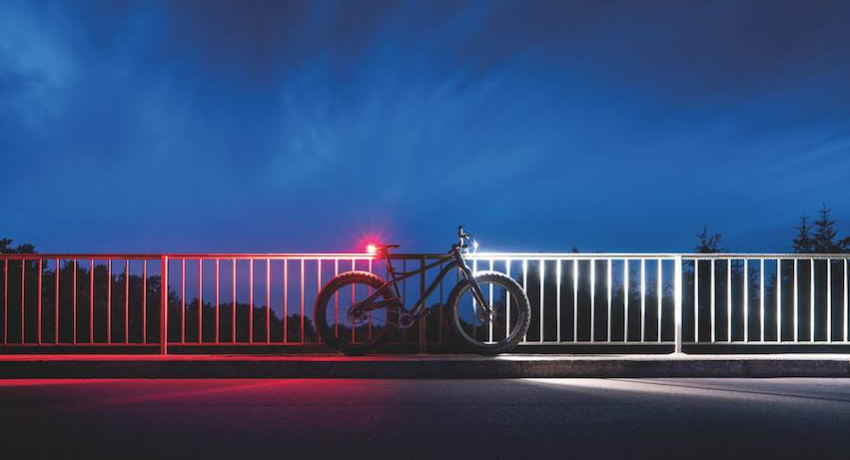 Vélo stationné la nuit avec éclairage blanc à l'avant et phare rouge à l'arrière