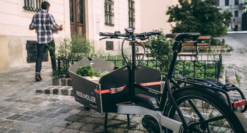 Homme en train de décharger une caisse d'un vélo cargo