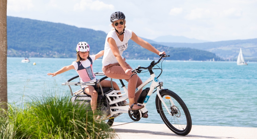 Mère et sa fille à vélo cargo devant un lac