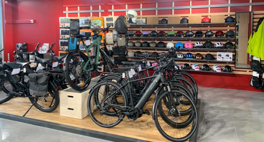 Devant le rayon des casques de vélo, une estrade réservée à une large sélection de vélos à assistance électrique dans le magasin de Cyclable Castelnau