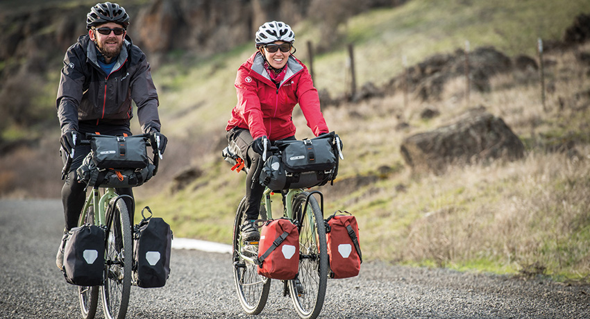 Deux cyclistes sur des vélos gravel roulant en pleine nature avec des sacoches de randonnée
