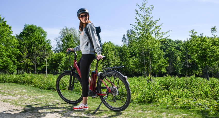 Une femme s'apprête à partir en randonnée dans la forêt avec un vélo électrique O2feel iVog Explorer