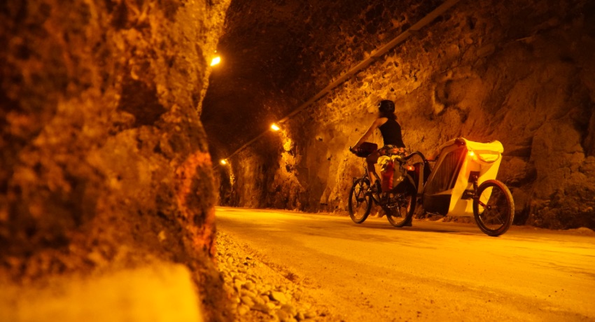 Une femme tractant une remorque pour enfant sous l'éclairage orangé du tunnel de Bois-Clair, en sud Bourgogne. 