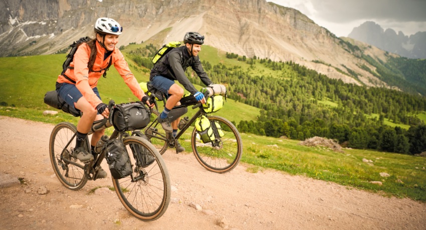 Une femme et un homme à vélo sur un chemin de montagne équipés d'une configuration bikepacking
