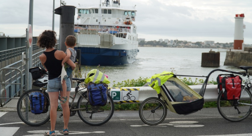 Une femme tenant son fils dans les bras patiente près de son vélo avant d'embarquer dans un ferry