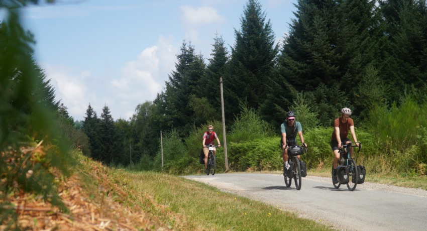 Trois cyclotouristes évoluant sur une petite route forestière sur la Mad Jacques Millevaches 