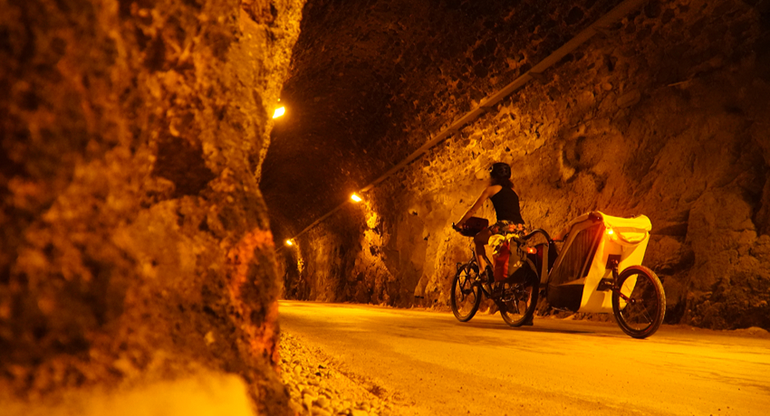 Une femme tractant une remorque pour enfant sous l'éclairage orangé du tunnel de Bois-Clair, en sud Bourgogne.