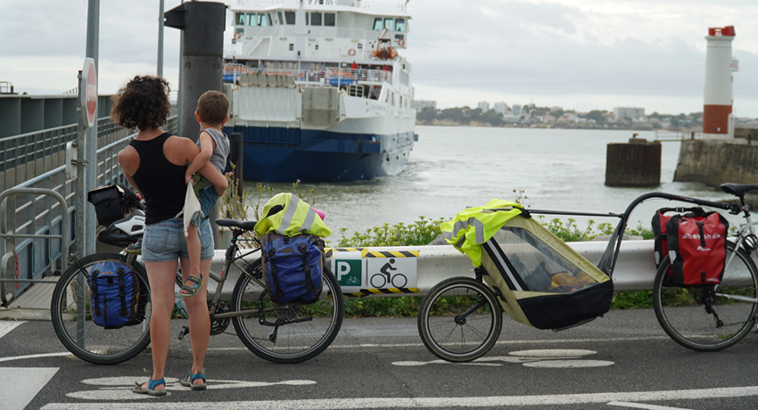 Une femme tenant son fils dans les bras patiente près de son vélo avant d'embarquer dans un ferry