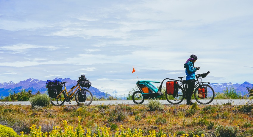 La famille marque une pause sur une petite route des Andes aves des sommets enneigés en toile de fond.