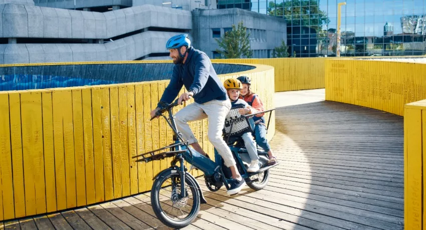 Un père et ses deux enfants en ville sur un vélo rallongé midtail Riese&Müller Multitinker.