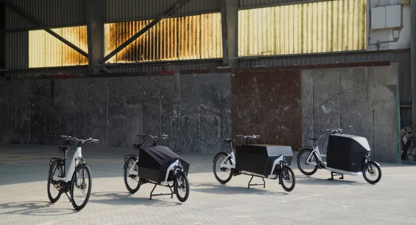 Des vélos cargos, biporteurs et longtail alignés dans un hangar.
