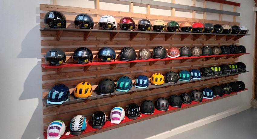 Des dizaines de casques de vélo exposés sur un présentoir du magasin Cyclable Champigny.