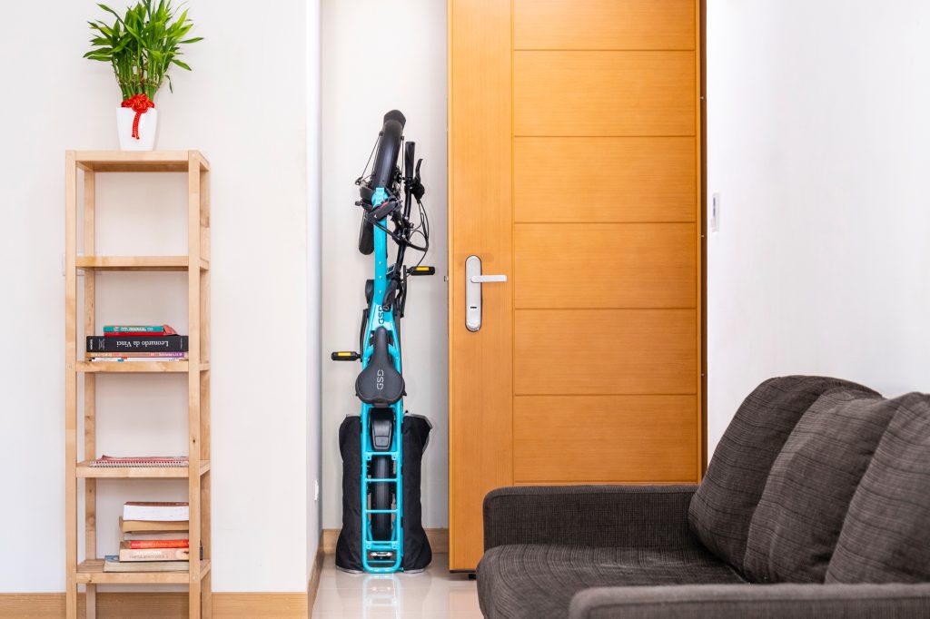 Un vélo cargo Terne GSD rangé à la vertical, guidon plié, le long d'un mur dans un appartement.