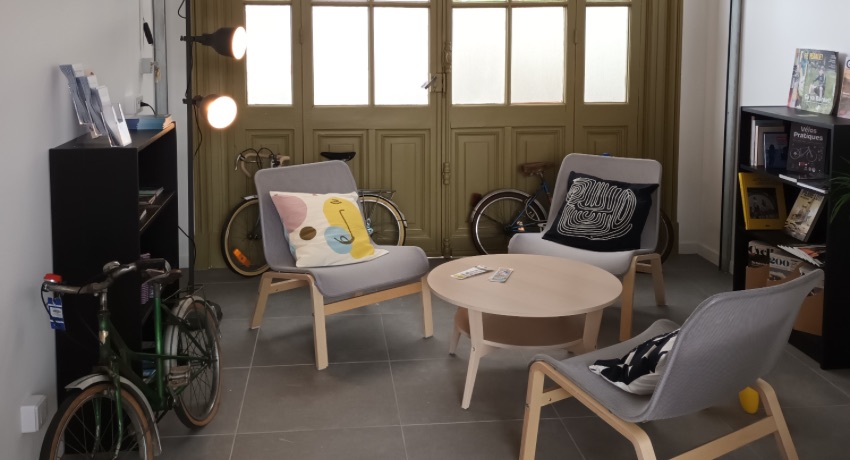 L'espace détente de la nouvelle Maison du vélo de Rochefort avec un une table, des fauteuils et des livres consacrés au vélo.