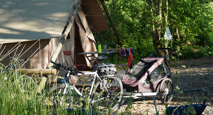 Un vélo de voyage et un remorque pour enfant stationnés devant une cabane de trappeur.