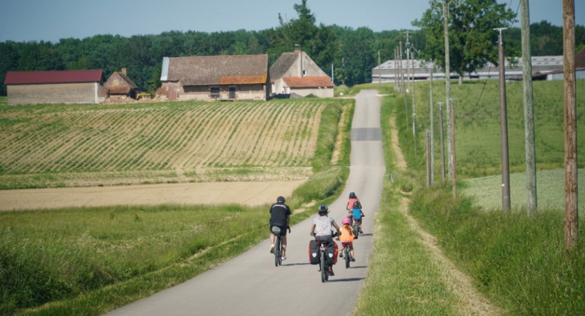 Une famille de cyclotouristes sur une petite route de campagne sur la Voie Bressane. 
