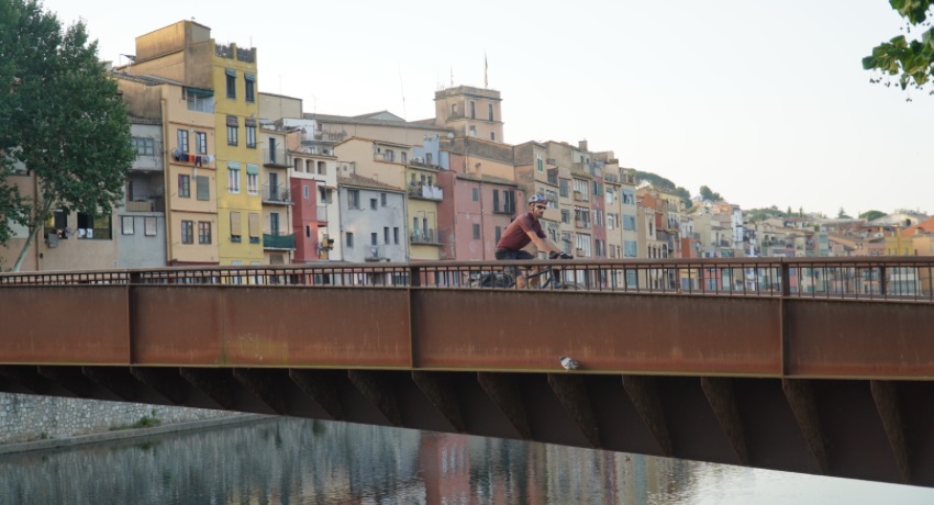 Un voyageur à vélo traverse un pont dans la vieille ville de Gérone.