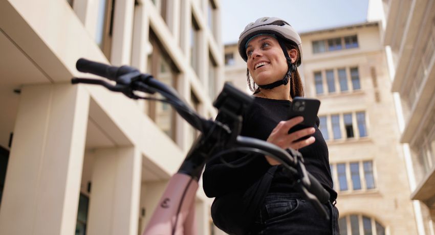 Une femme dans une cour d'immeuble consulte l'application Bosch eBike Flo avant d'enfourcher son vélo électrique.