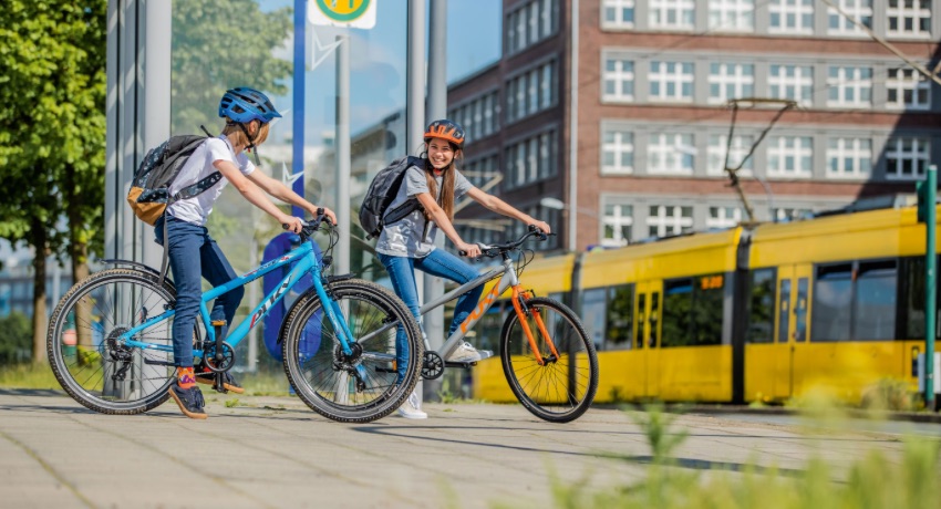 Une jeune fille et un jeune garçon sac d'école sur le dos discute à l'arrêt sur le vélo prêt d'un arrêt de bus. 