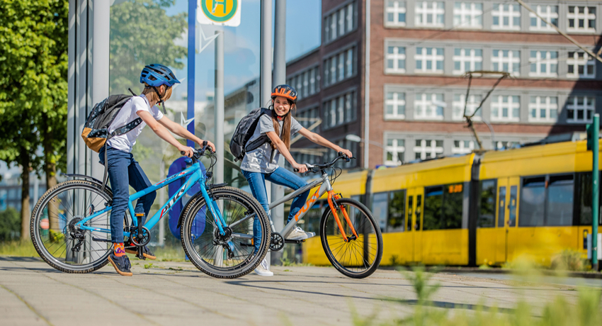 Une jeune fille et un jeune garçon sac d'école sur le dos discute à l'arrêt sur le vélo prêt d'un arrêt de bus.
