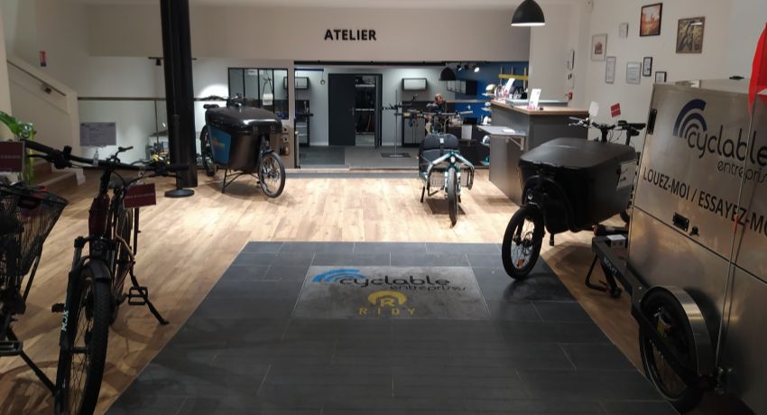 Le hall d'entrée de l'espace Cyclable Entreprises Paris 13 avec des biporteurs XXL et une remorque grand format.