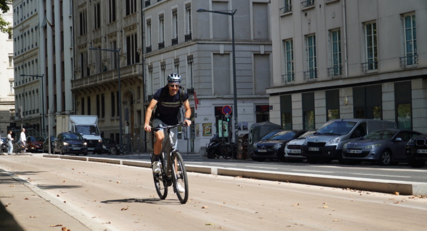 Un cycliste sur une piste cyclable urbaine chevauche en danseuse un Kalkhoff Endeavour L.