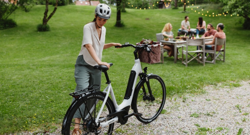 Une cycliste béquille son VAE Winora Tria X9 en arrivant dans un parc où est organisé un pique-nique.