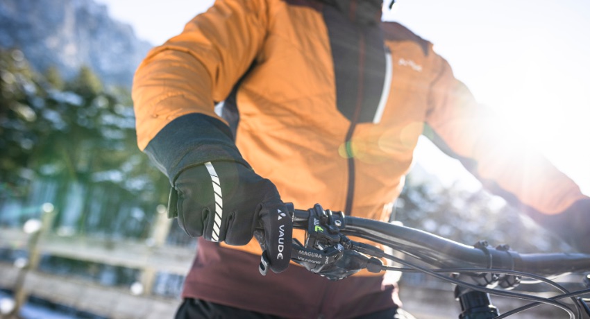 Gros plan sur une main gantée posée sur le levier de frein d'un vélo en hiver.