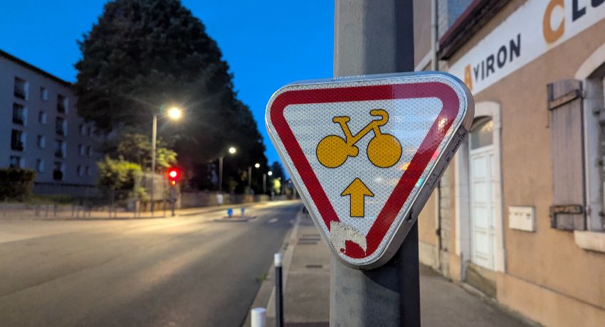 Un panneau M12 avec une flèche directionnelle à un feu rouge autorisant les cyclistes à franchir le carrefour à la manière d'un cédez-le-passage.