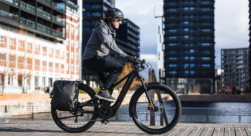 Un homme casqué pédale en ville au guidon d'un speed bike.