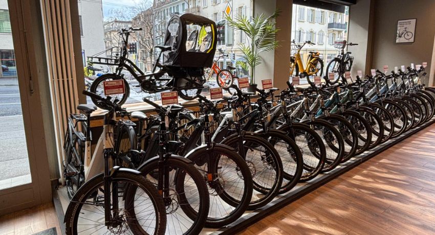 Vue intérieure de la vitrine de Cyclable Lausanne Malley avec un shortail et longue rangée de VAE urbains.