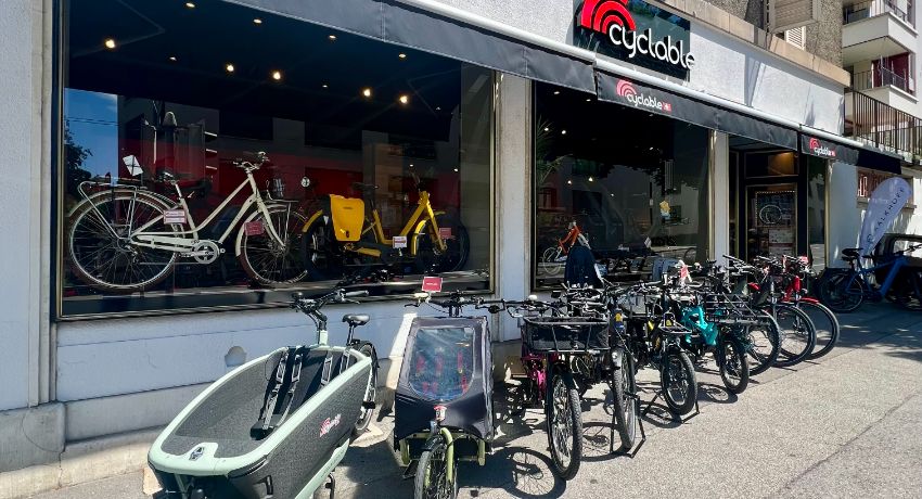 Des vélos cargos et VAE exposés en extérieur devant la vitrine de Cyclable Lausanne Malley.